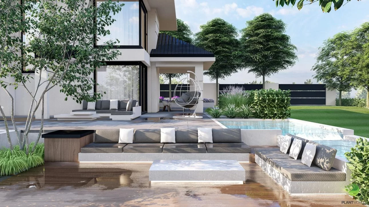 Modern backyard with sunken seating area next to pool, gray cushions, white table, patio with hanging egg chair and large glass windows. A green lawn and trees surround the contemporary house.