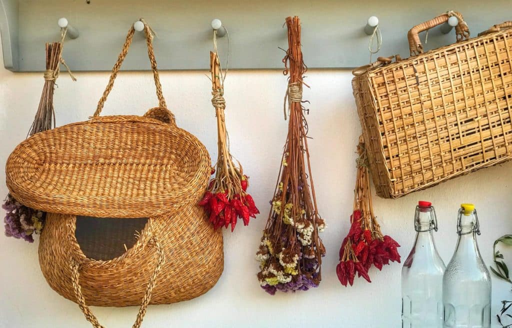 Wicker baskets and flowers hanging on a hook in a kitchen.